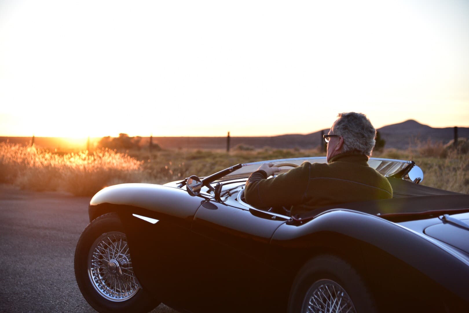 Collector seated in a roadster at sunset